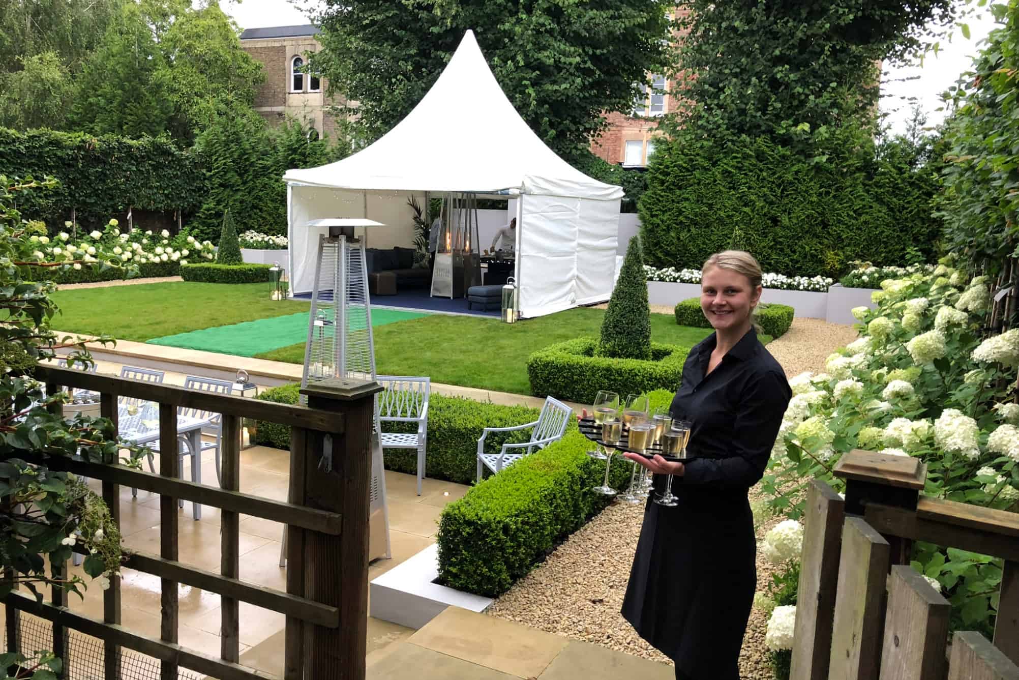 Event staff serving champagne in front of a Chinese hat marquee