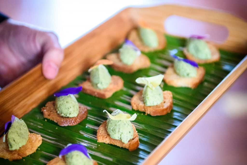 Pea and mint canape with edible flowers beautifully displayed on a tray with a banana leaf